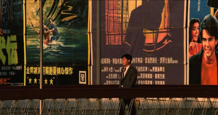 走在天橋上，背後的電影海報全部都是國外電影。