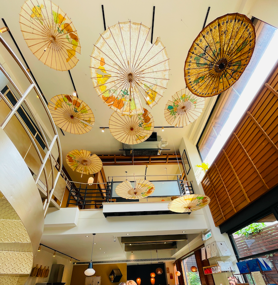 手作的竹傘掛在兩層樓之間，具日式風格。
