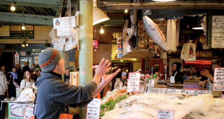 派克市場的丟魚秀，魚販正將一條肥美的魚二兒往上拋的精彩畫面。（圖截自網路）