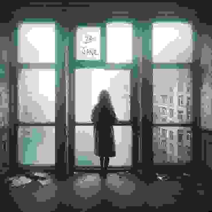 In the midst of a misty cityscape, an urban woman stands by a large window on the 23rd floor of an old building.