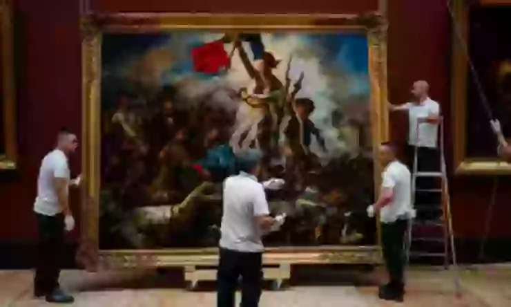 羅浮宮工作人員將清潔後的畫作掛回展廳（圖片來源：Dimitar Dilkoff/AFP ）