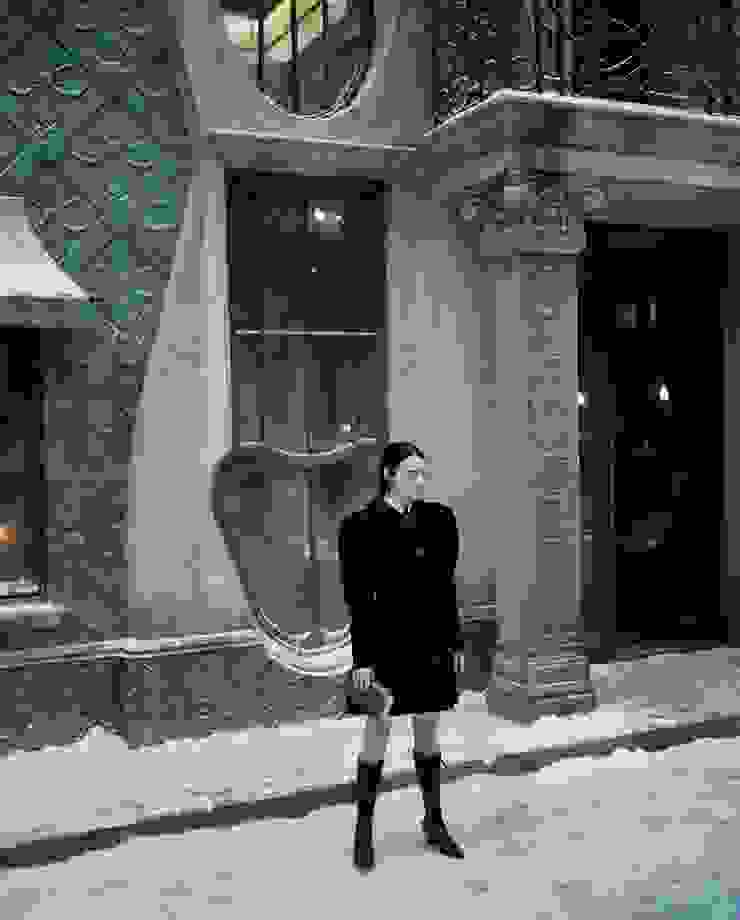 電影《可憐的東西》劇照。Emma Stone飾演的主角貝拉拿著書本，一身又帥又美的造型，佇立在雪地中，她背後的建築物有著以陰莖為樣式的巨型窗戶。