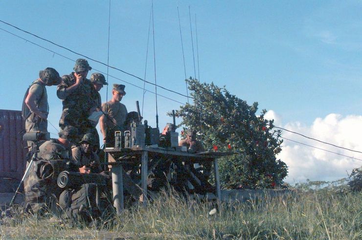 ANGLICO兼具FAC和火砲觀察員的職能,為部隊協調引導航空與火炮支援,能乘坐軍機或以地面小隊的方式執勤。而其特殊之處在於ANGLICO負責的是在跨軍種或跨國籍聯合行動中,為與海軍陸戰隊相鄰的盟國與其他軍種提供引導與協調,桌上的無線電與雷射指示器就是他們最強大的武器(注意此圖中出現的雷射指示器是90年代末服役的AN/PEQ-1而非波斯灣戰爭期間使用的AN/PAQ-3)。ANGLICO最小也最常見的單位是火力控制小組(FCT),由具備聯合終端攻擊管制員資質的上尉指揮2-3名負責無線電或前沿偵查的陸戰隊;而在此戰中,邊境的FCT又進一步拆分成2個小組輪流在邊境值勤。兩個FCT加上一個8人指揮組組成一個支援武器聯絡隊(SALT),指揮組和營級單位合作管理運作旗下的FCT。