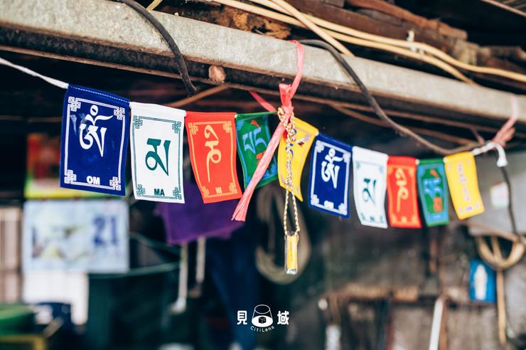 店門口掛著印有六字真言「唵嘛呢叭咪吽」的西藏五色旗，保佑出入平安。